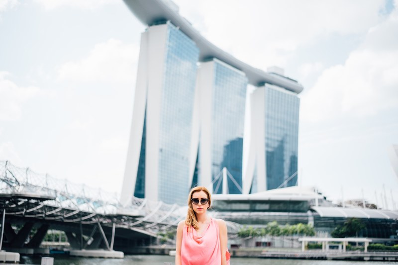 a girl wearing a pink dress and black sunglasses standing in front of marina bay sands in singapore, marina bay sands 4k