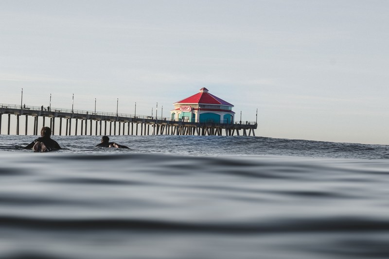 two swimmers and the pier in the background viewed from the water surface at huntington beach, swimmers and the pier 4k