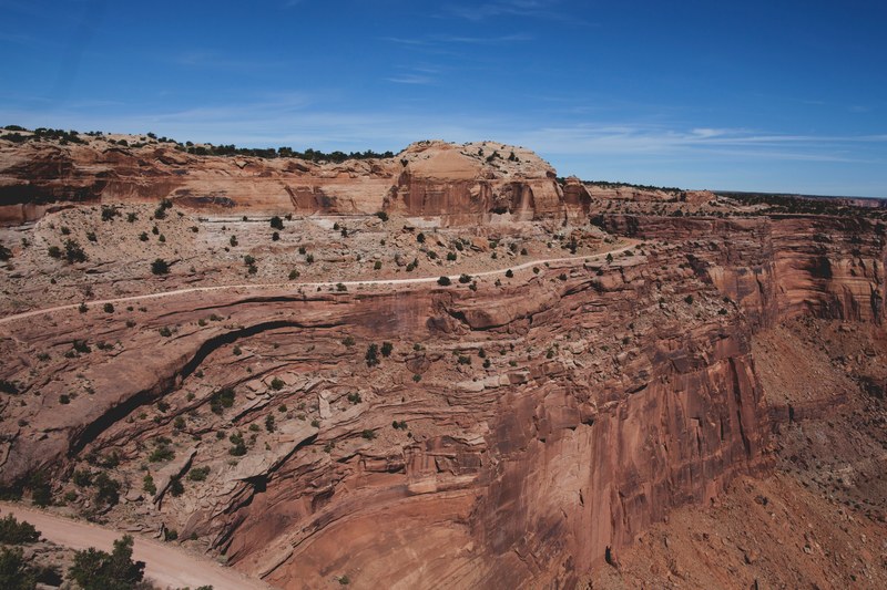 a canyon wall enveloped by a dusty road on a hot day, dusty canyon road 4k