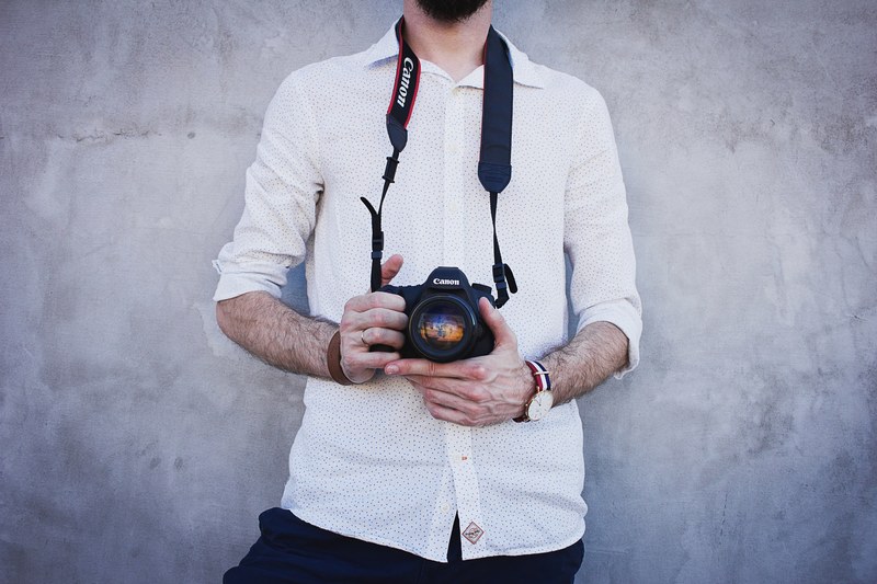 a man in a white polka dotted shirt holding a canon camera in olsztyn, olsztyn canon camera 4k