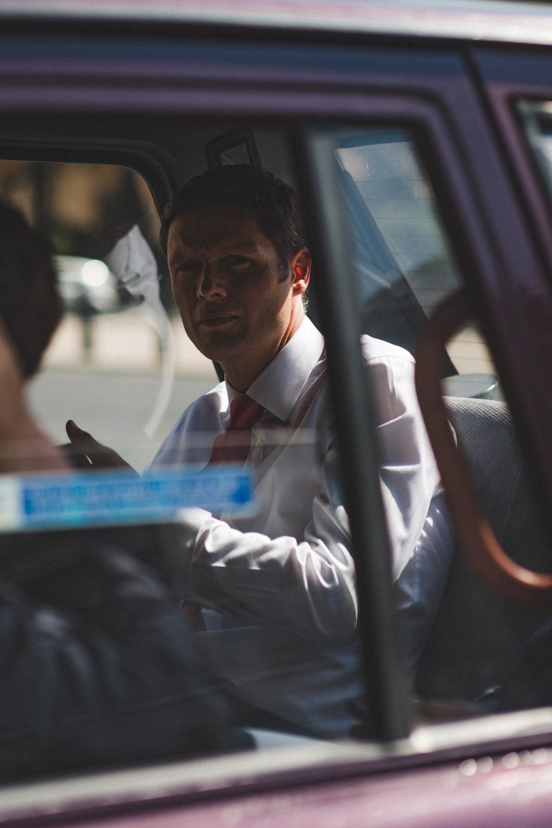 a man in a white shirt and a red tie in the back seat of a car, modern affairs 4k