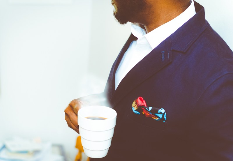 a man in a navy blue jacket holding a cup of hot coffee, elegant man with hot coffee 4k