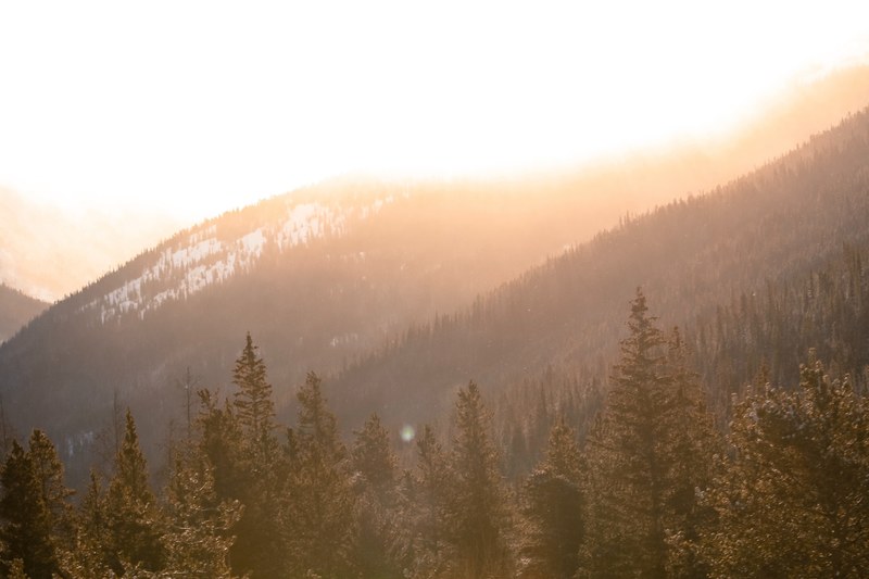 the sun setting over a sloping mountainside forest, sunset over the mountain forest 4k