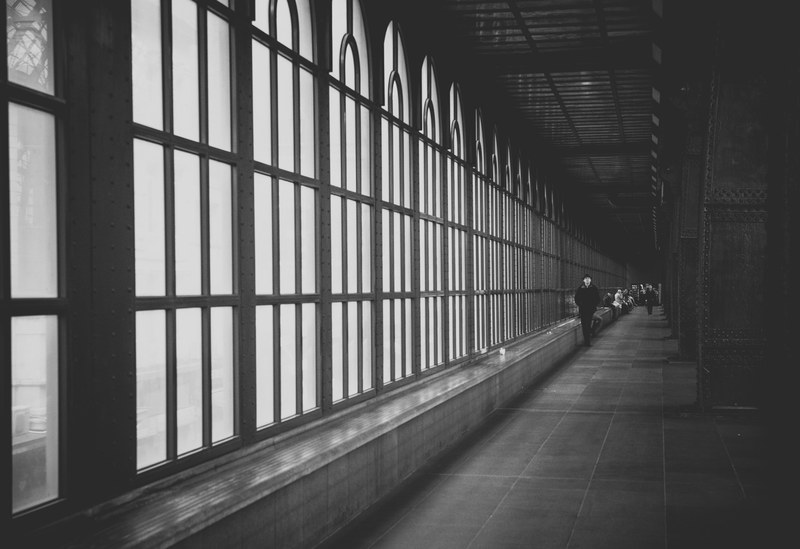 black and white shot of hallway architecture with large windows and person walking, monochrome hallway person 4k