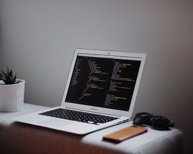 open laptop on desk displaying programming code near sunglasses a phone and a plant, laptop open with code 4k