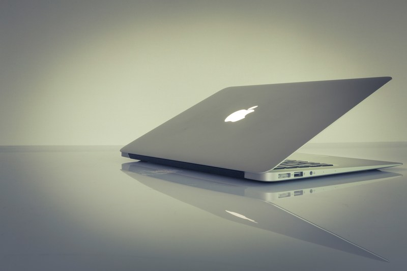 a half closed macbook on a reflective surface, half closed laptop 4k