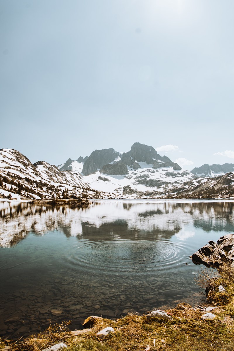 a crystal clear garnet lake with snowy mountains in the distance, snow caps 4k