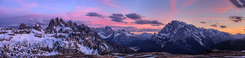 a magnificent landscape with tall craggy mountains under a purple hued sky in the dolomites, dolomites panorama 4k