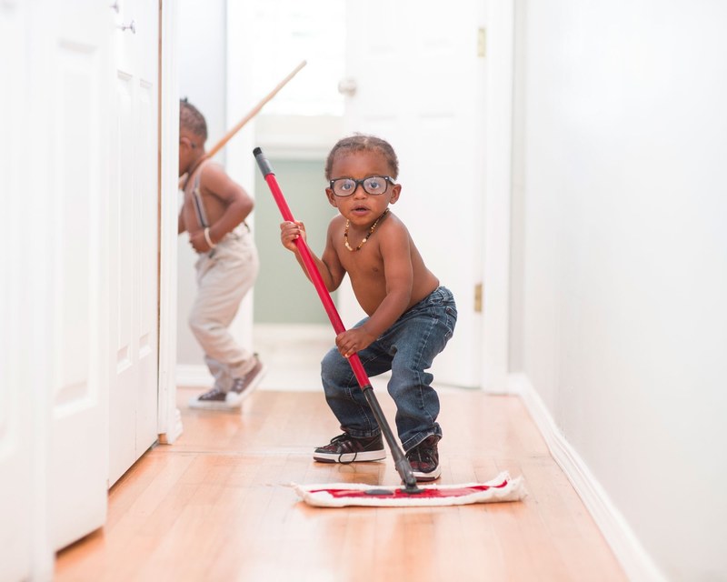 a funny african american boy with glasses using a push mop to clean the haul away, _boy mopping 4k