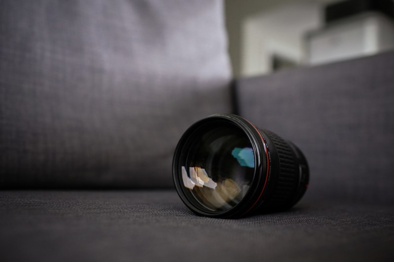 black camera lens sits on gray sofa, camera on sofa 4k