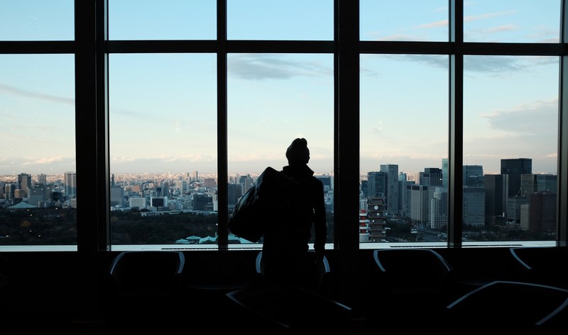 a silhouette of a person staring out large office building windows at the citys architecture, staring out building windows 4k