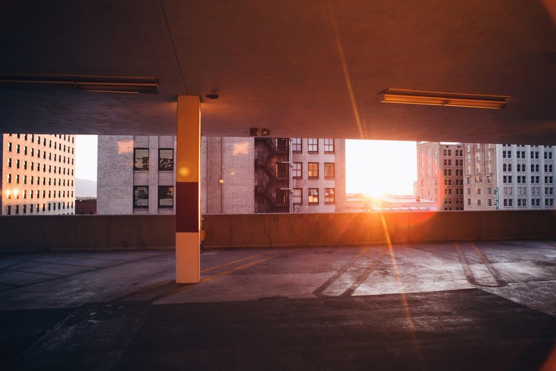sun peeking through an empty city car park next to buildings in salt lake city, car park salt lake city 4k