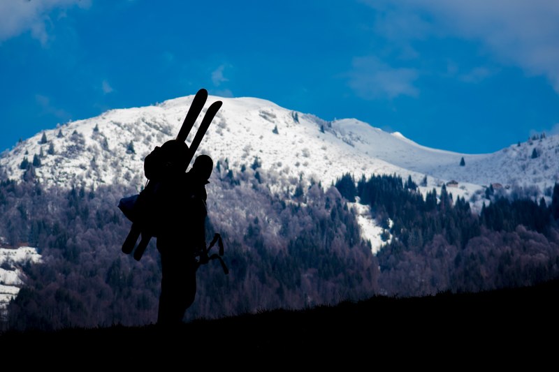silhouette of a skier ascending a snowy blue mountain landscape, skiers silhouette 4k