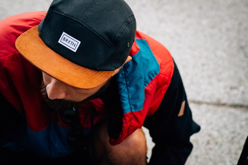 a bearded man in a baseball cap and brightly colored jacket kneels lowering his head, kneeling man in baseball cap 4k