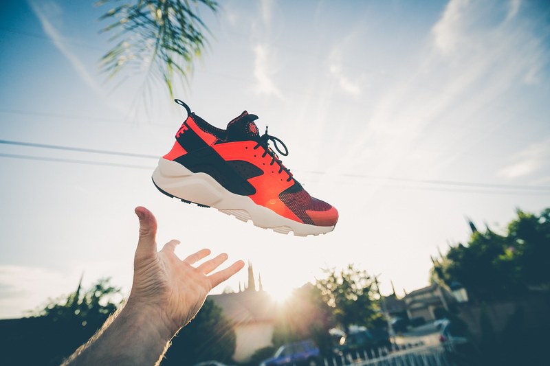 man tossing red shoes up in the air from his hands, man throwing shoes in air 4k