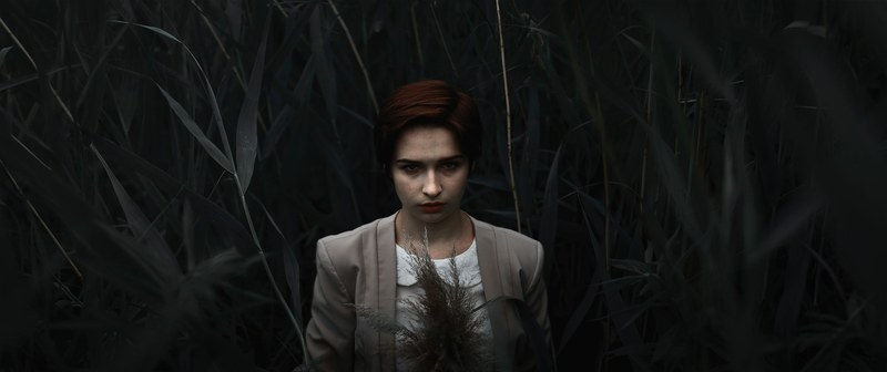 sad person standing alone in a dark leafy forest, stern looks 4k