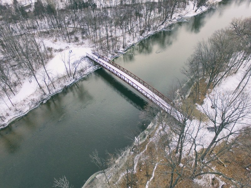 aerial view of a bridge crossing a river surrounded by a winter landscape, over the river 4k