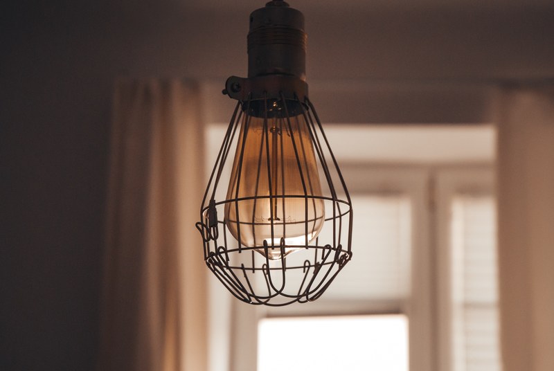 vintage lightbulb in wire cage casing hanging from a room ceiling, light bulb in a wire cage 4k