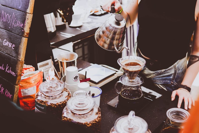 a woman with tattoos pouring coffee into a filter from a kettle in a cafe in stanbul, waitin for the tasty 4k
