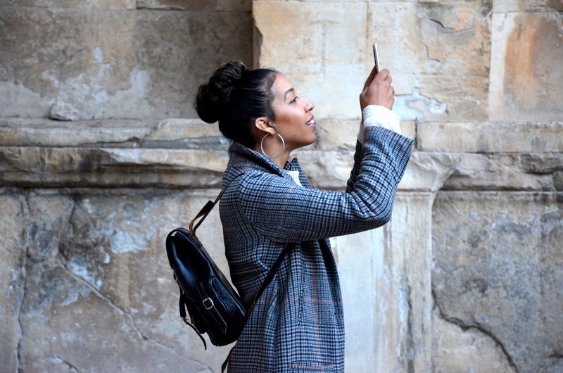 a female tourist smiling while taking a photograph with a smartphone, taking a selfie 4k