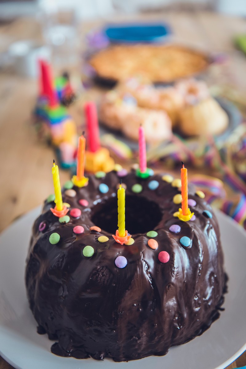 a chocolate covered bundt birthday cake with coloured candy and candles on top, birthday bundt cake 4k