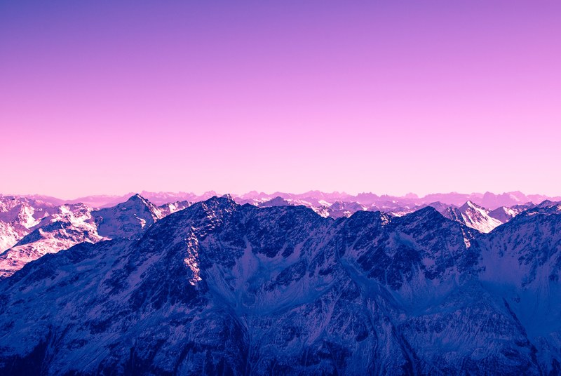 a pink hued sky over tall snow capped mountains in austria, pink sky over mountains 4k