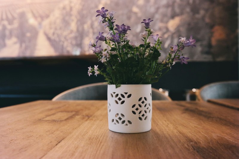 white and violet flowers in a white flowerpot on a wooden table, violet flowers on a table 4k