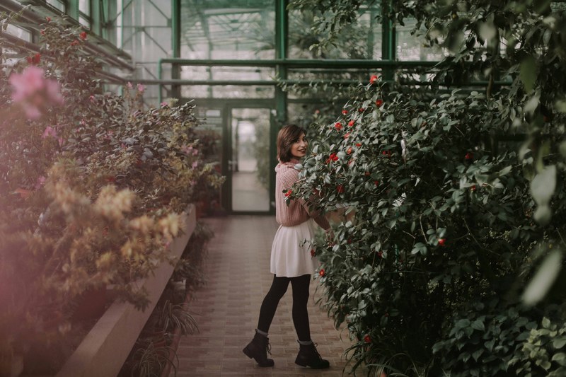 a young woman smiling to the camera in a botanical garden, we found spring this winter 4k