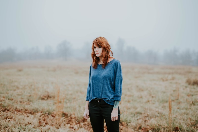 woman stands in a desolate field deep in thought, countryside contemplation 4k