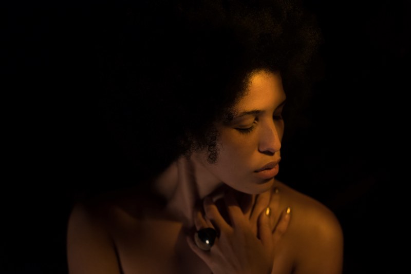 woman wearing ring with curly hair poses in dark lighting with eyes closed a, a broken heart_ 4k