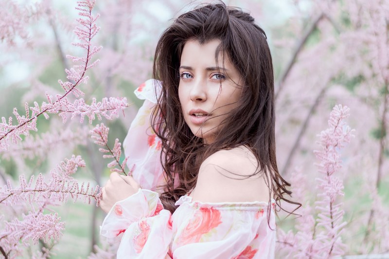 woman wearing a flowy floral top standing in flowers, feminine florals 4k