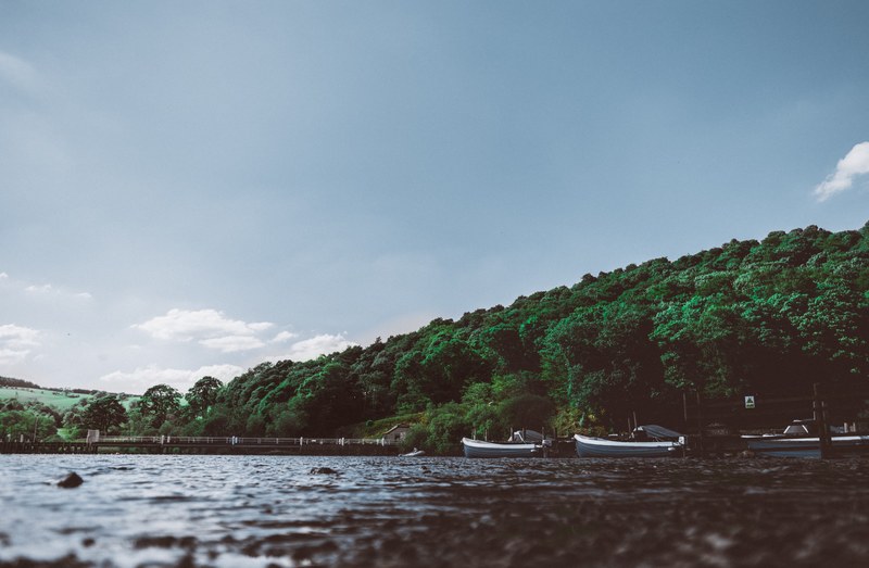 boats moored at the shore of a choppy lake, boats on ullswater lake 4k