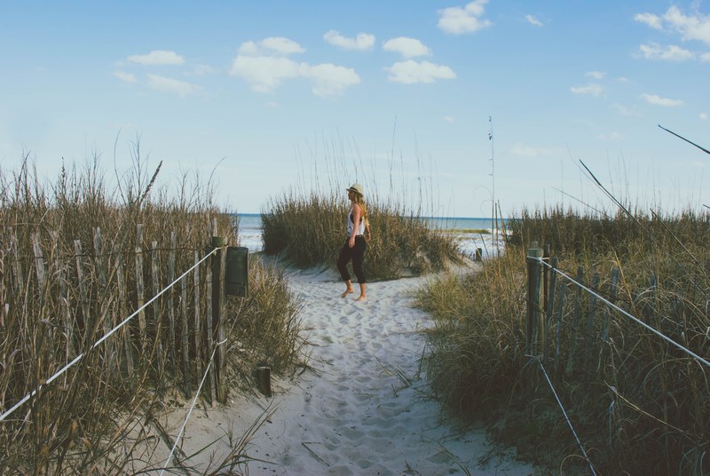 woman with a hat on the grass covered sand beach at myrtle beach, woman on the sand beach 4k