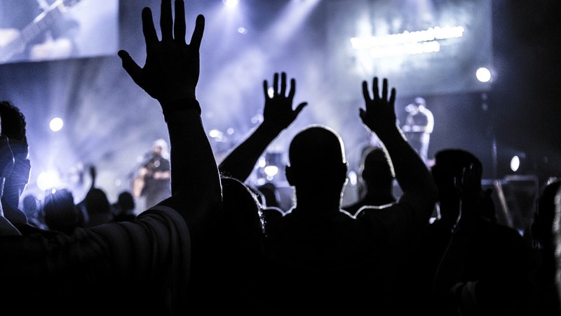 concertgoers raising their open hands in the air silhouetted against the illuminated stage in houston, houston audience lifting up hands 4k