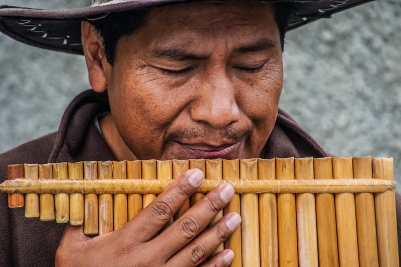 a man in a hat playing the panflute on madeira, panflute player 4k