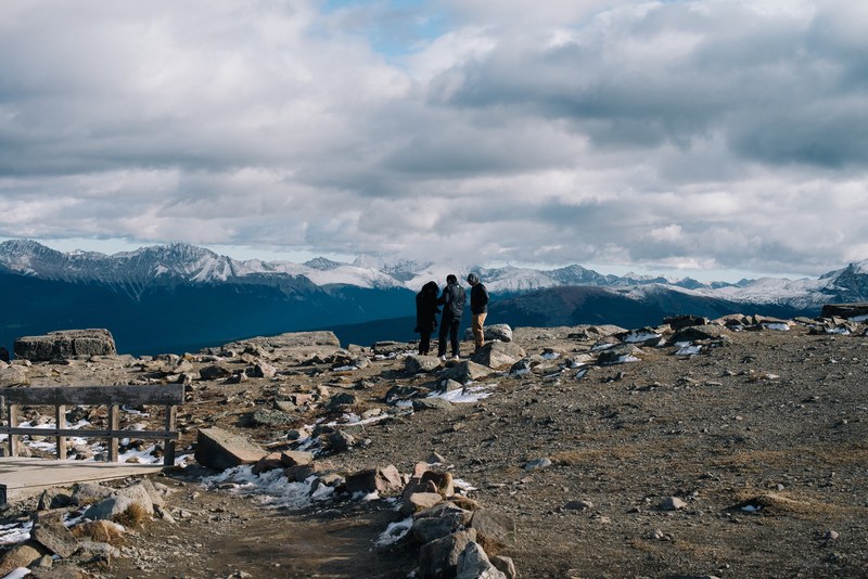 three people stand on a barren mountain in jasper, group of people at jasper mountain 4k