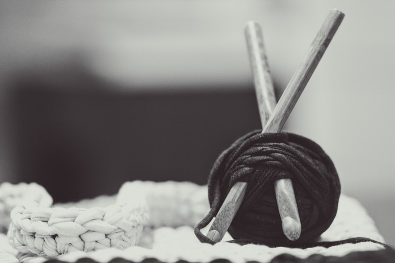 a black and white shot of yarn wrapped around crocheting hooks, crocheting in black and white 4k