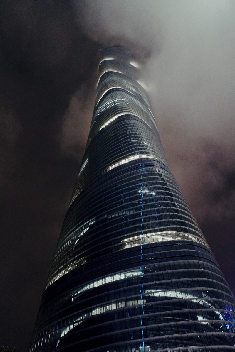 a tall twisting skyscraper in thick fog on an evening, shanghai tower 4k