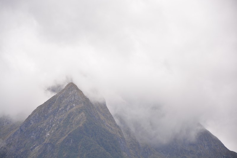 a thick mist rolling down the moss covered slopes of a tall mountain, fog shrouded mountain 4k