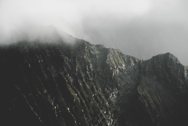 a craggy mountain ridge in mount aspiring national park under thick fog, cliff 4k