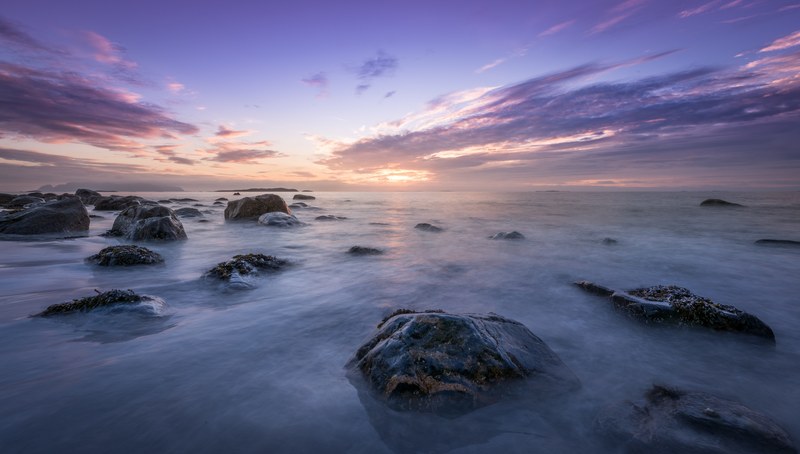 a scenic shot of the clouds and sunset rising from the horizon above a norwegian sea, sunset over a sea in fl 4k