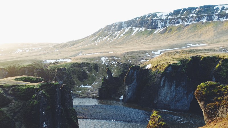 a river near a slight mountain slope covered with patches of snow, icelandic mountain river 4k