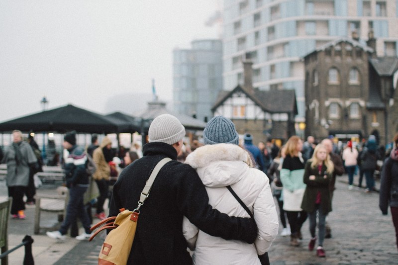 romantic couple traveling together walks in an embrace through a quaint town, touring the town 4k