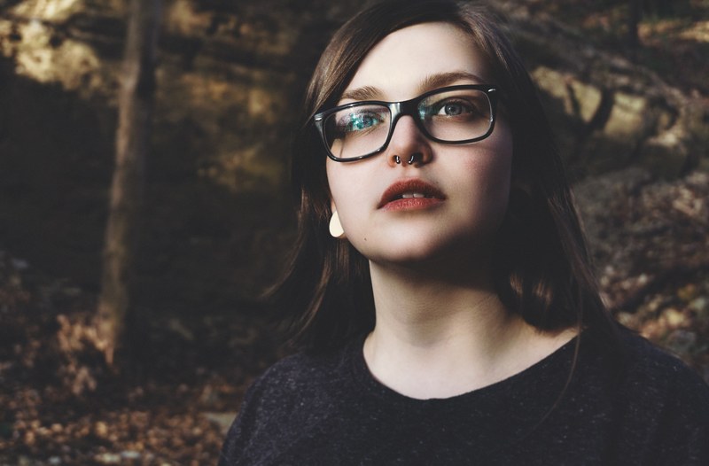 trendy young woman with a nose ring and glasses looks up, nose ring and glasses 4k
