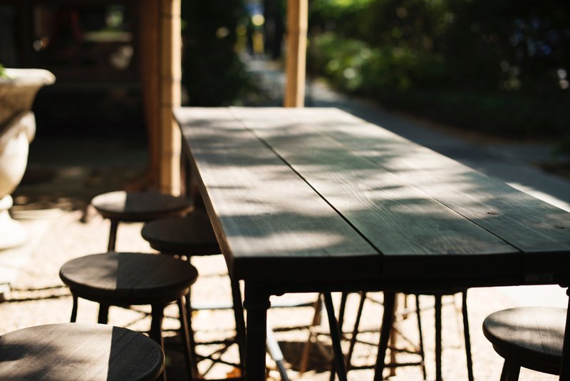 empty wood table with stools on an outdoor patio, restaurant patio furniture 4k