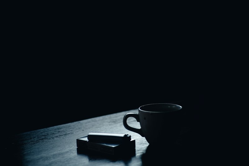 a dim shot of a pack of cigarettes and a lighter next to a teacup, coffee in cigarettes 4k