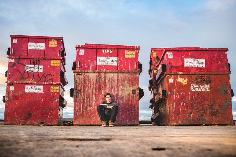 a person sitting by garbage dumpsters near the water in boulder colorado, sitting outside in boulder 4k