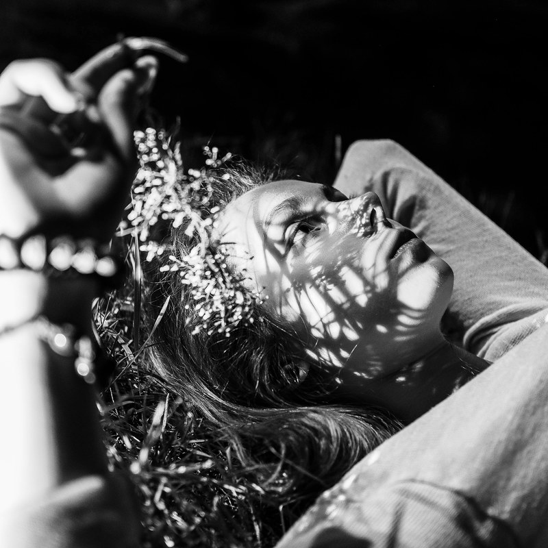 a black and white shot of a woman laying down on grass, woman on grass in black and white 4k