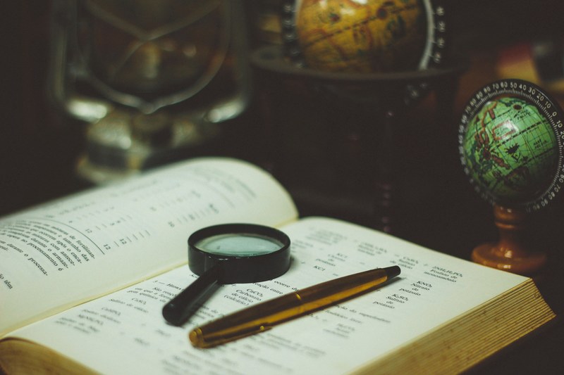 a book with a magnifying glass on top of it next to a pen and globes on a desk in cianorte, cianorte desktop 4k