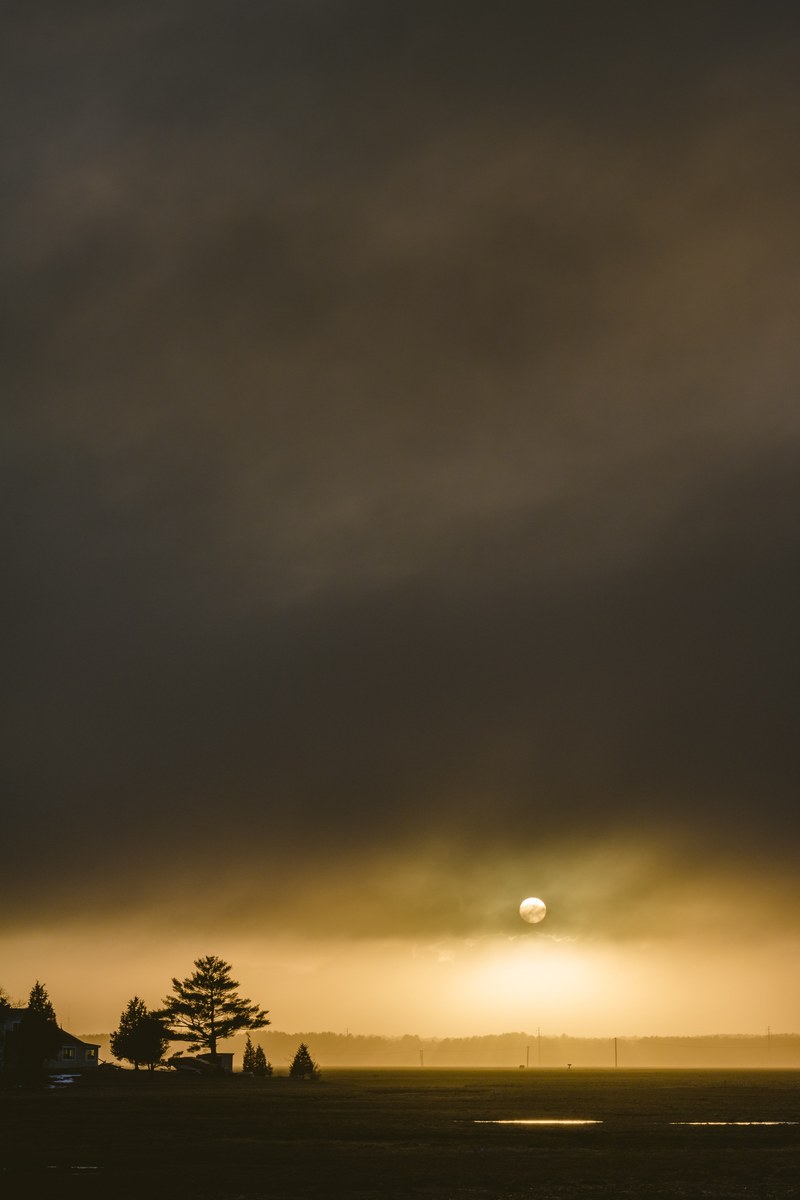 dark storm clouds surrounding the sun over a farm in new hampshire, end of times 4k